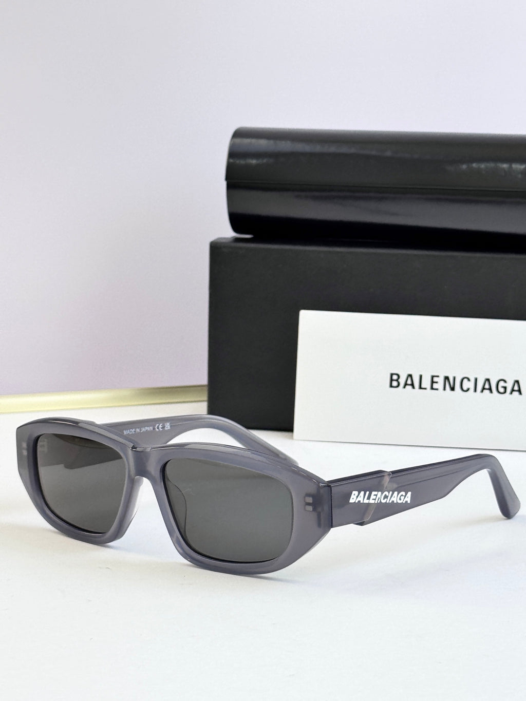 Gray sunglasses with dark lenses and Balenciaga logo on temple arms