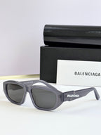 Gray sunglasses with dark lenses and Balenciaga logo on temple arms