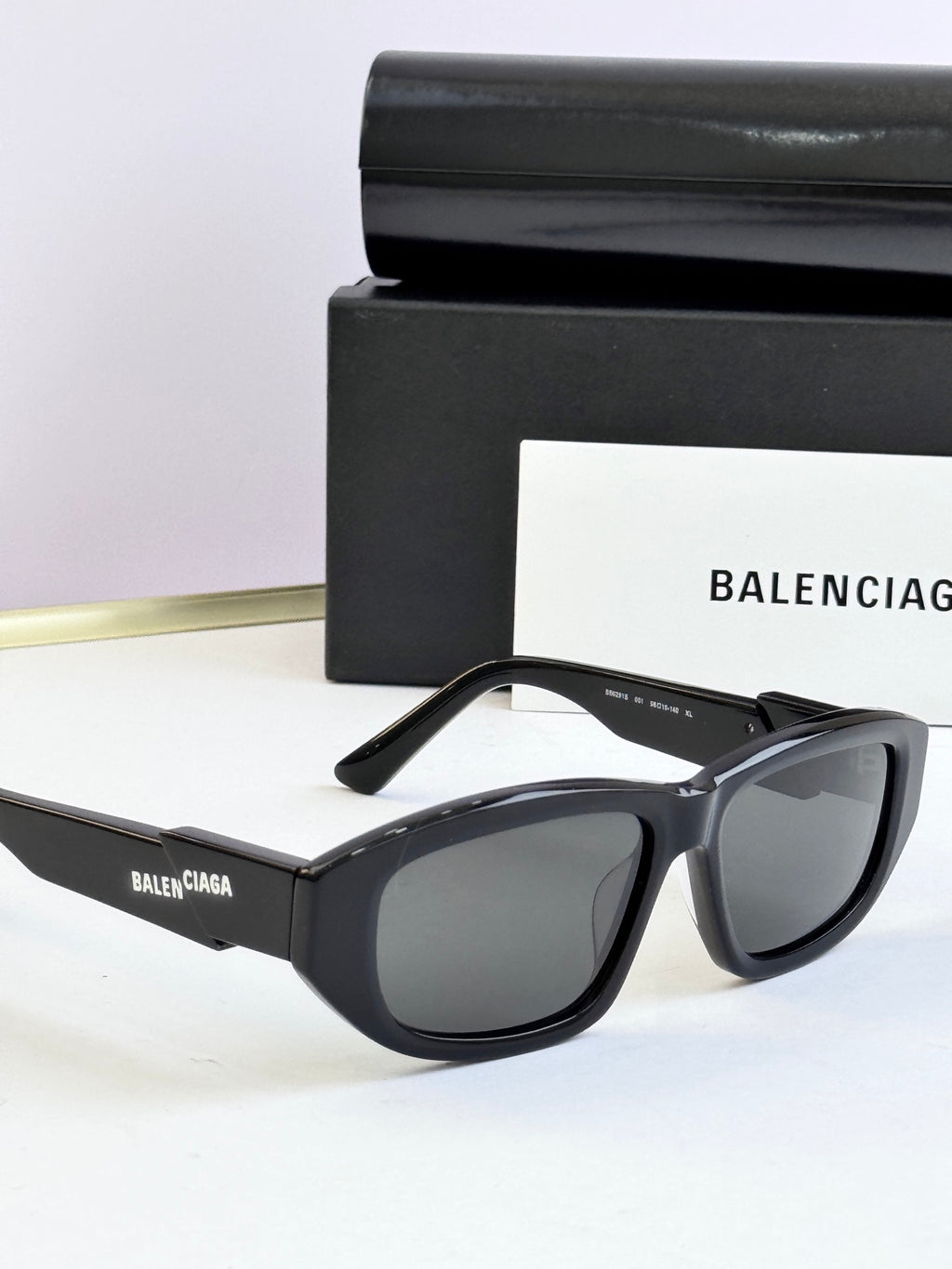 Black sunglasses with dark lenses and Balenciaga logo on temple strap