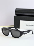 Black sunglasses with dark lenses and Balenciaga logo on temple arms