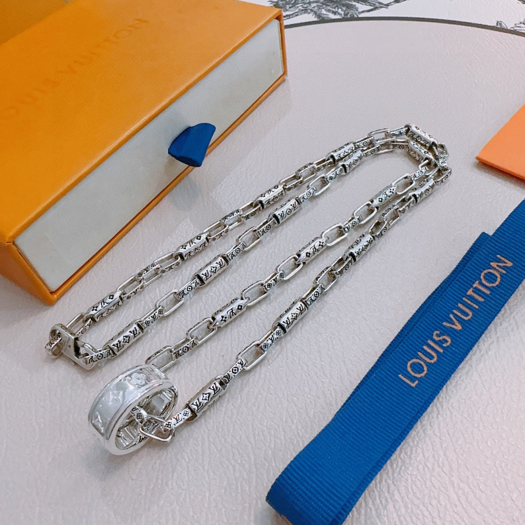 Silver chain necklace with charm clasp and engraved links, draped across display