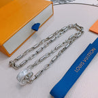 Silver chain necklace with charm clasp and engraved links, draped across display