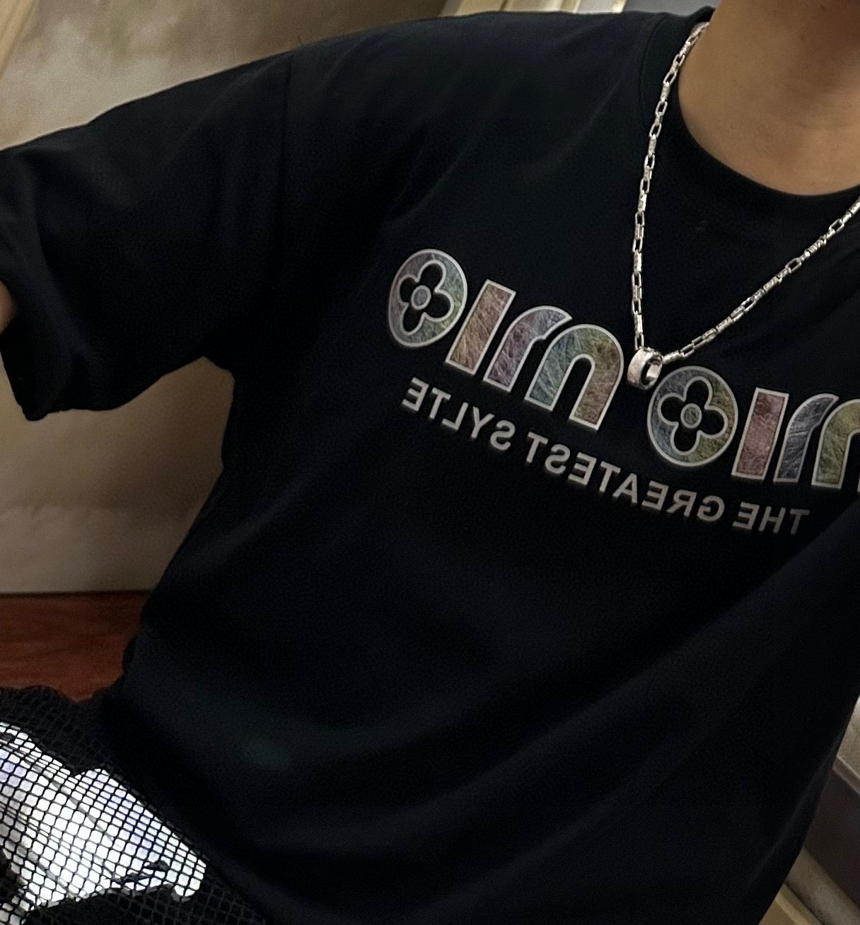 Black graphic T-shirt with silver chain necklace and small pendant at chest