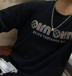 Black graphic T-shirt with silver chain necklace and small pendant at neckline