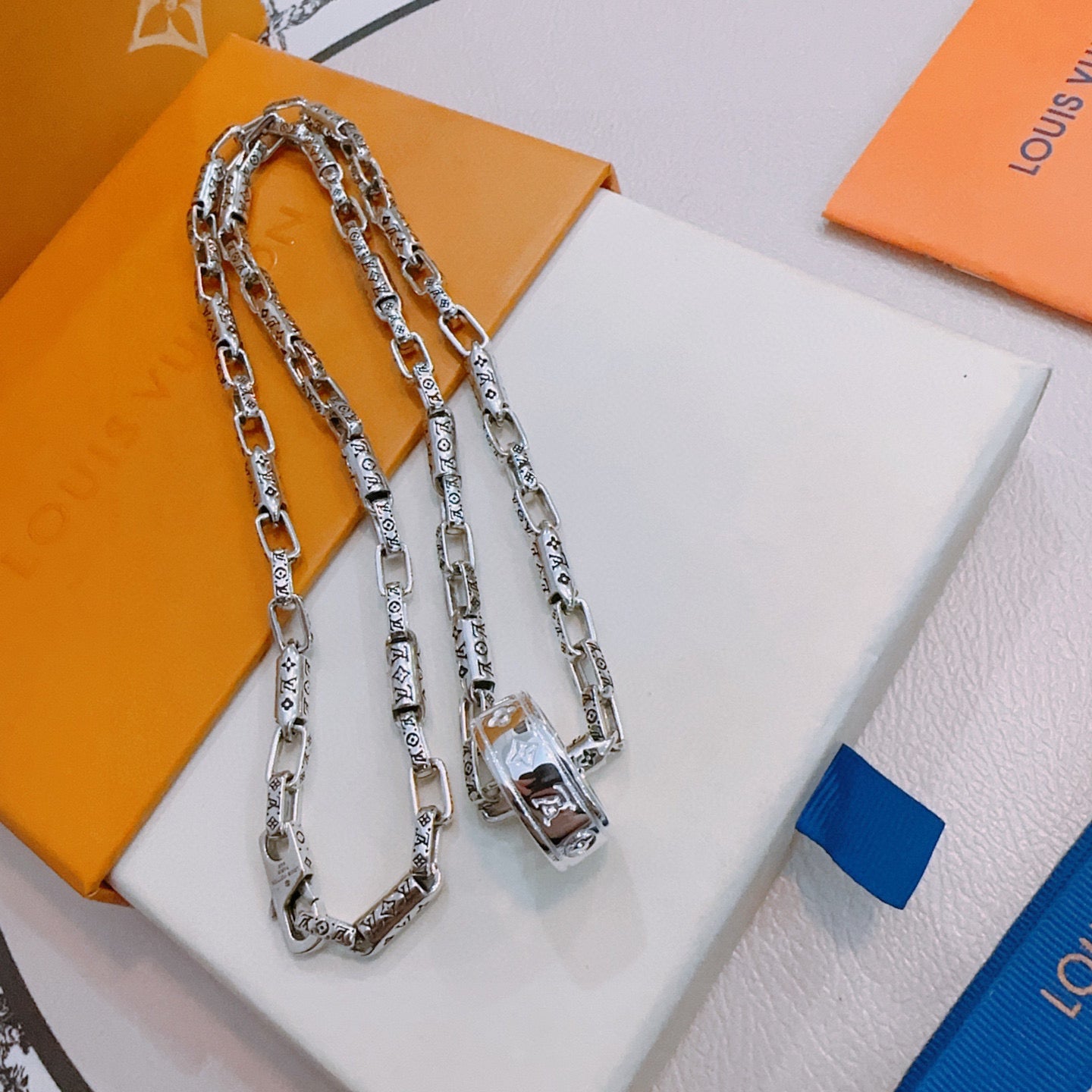 Silver chain necklace with rectangular charm and lobster clasp on display