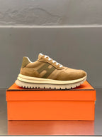 Tan lace-up sneakers with white laces and contrasting panels, side view on box