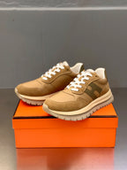 Beige and brown lace-up sneakers with white laces, pair on orange box