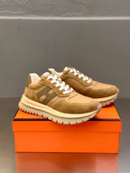 Tan lace-up sneakers with white laces, side view on orange box