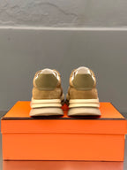 Back view of tan lace-up sneakers with white laces, on orange box