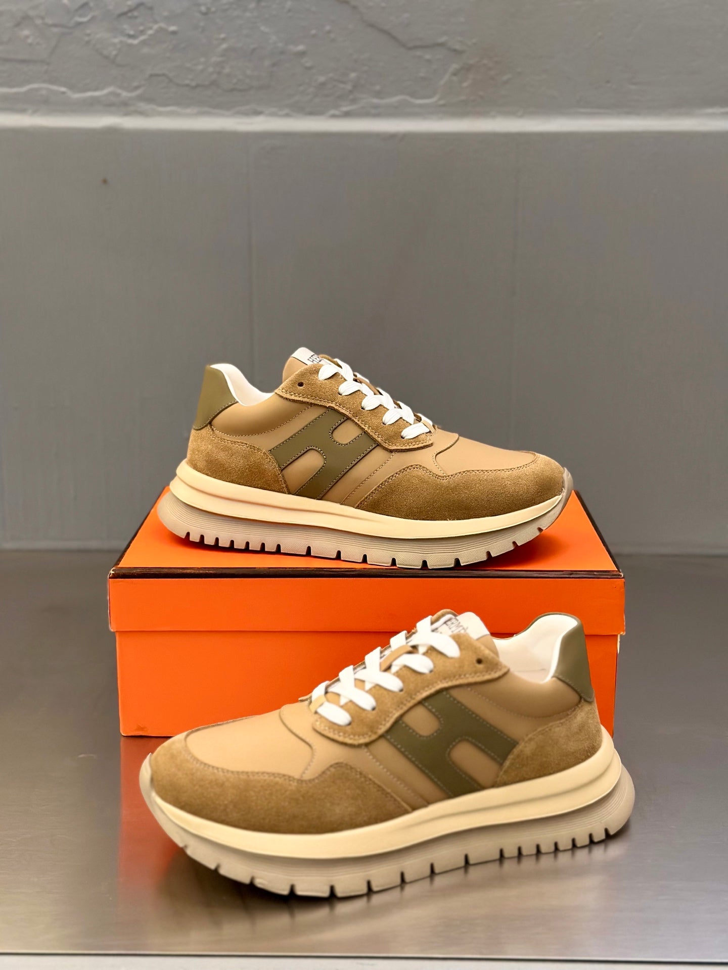 Brown and beige lace-up sneakers with white laces, side/front angle on box