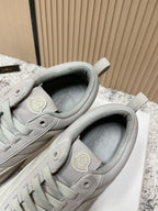 Light gray sneakers with padded collar and circular Moncler patch at heel