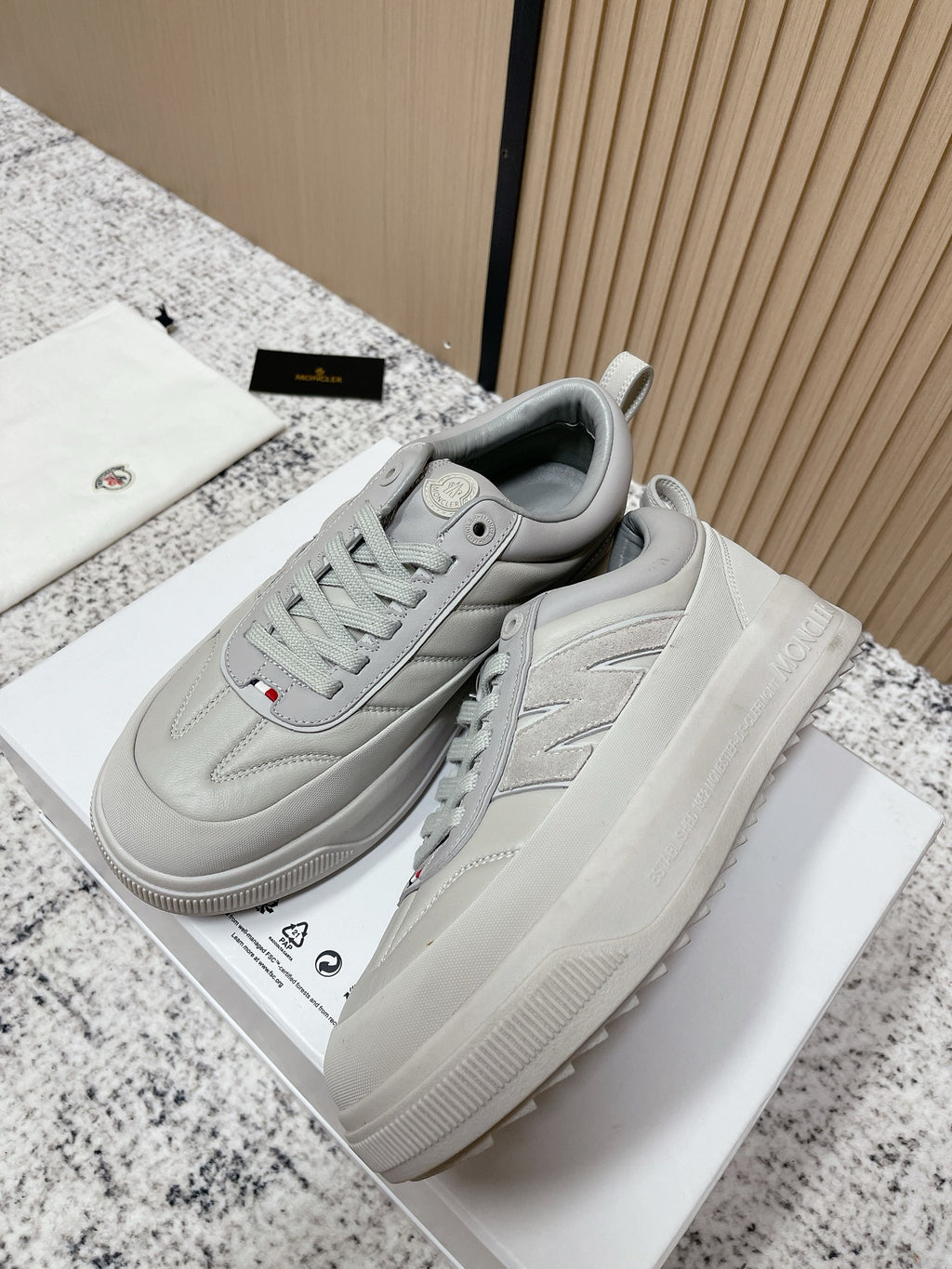 Light gray low-top sneakers with side logo and chunky rubber sole, lace-up style