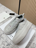 Light gray low-top sneakers with side logo and chunky rubber sole, lace-up style