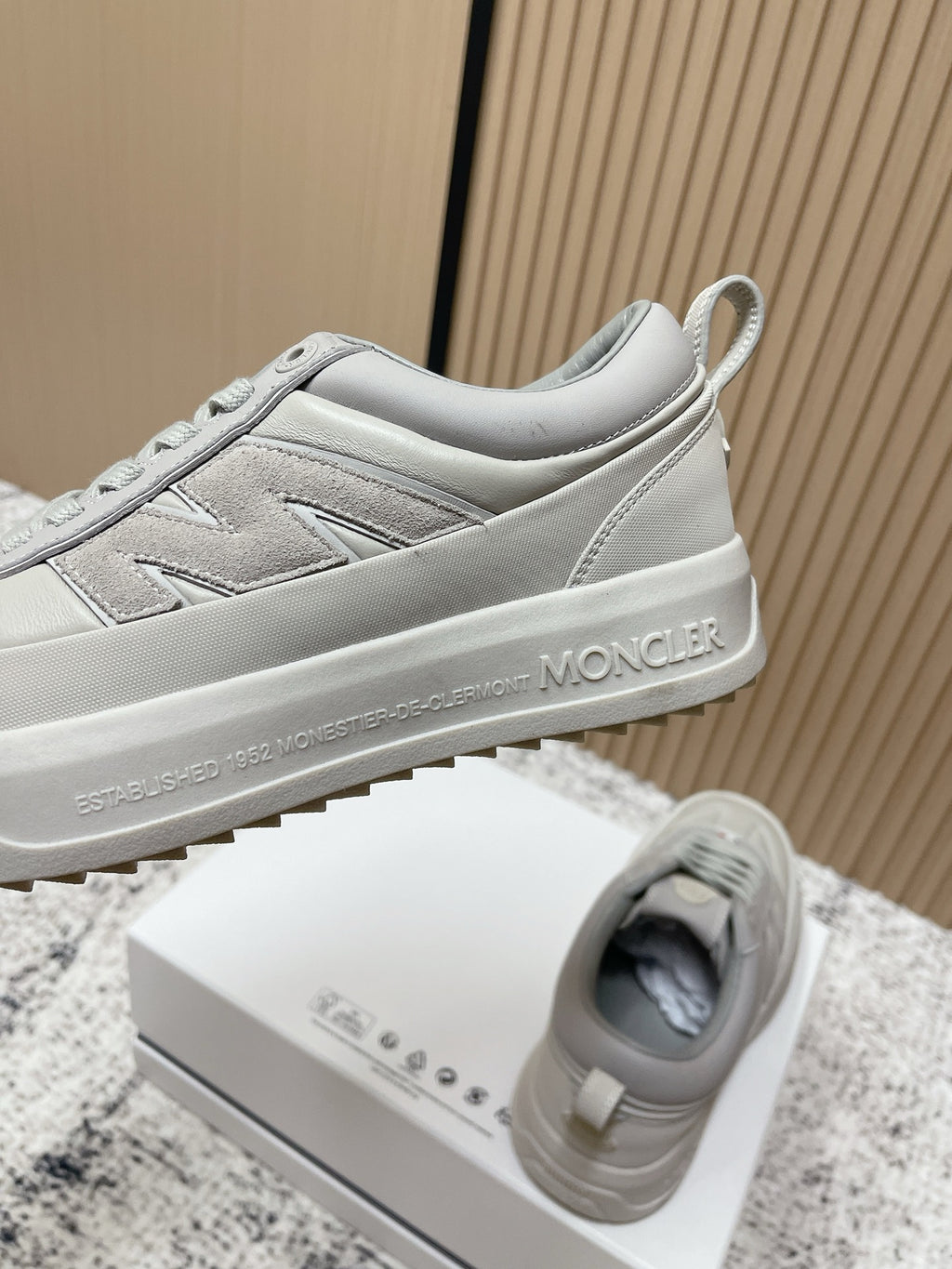 Light gray Moncler low-top sneakers with side panel stitching and heel logo text