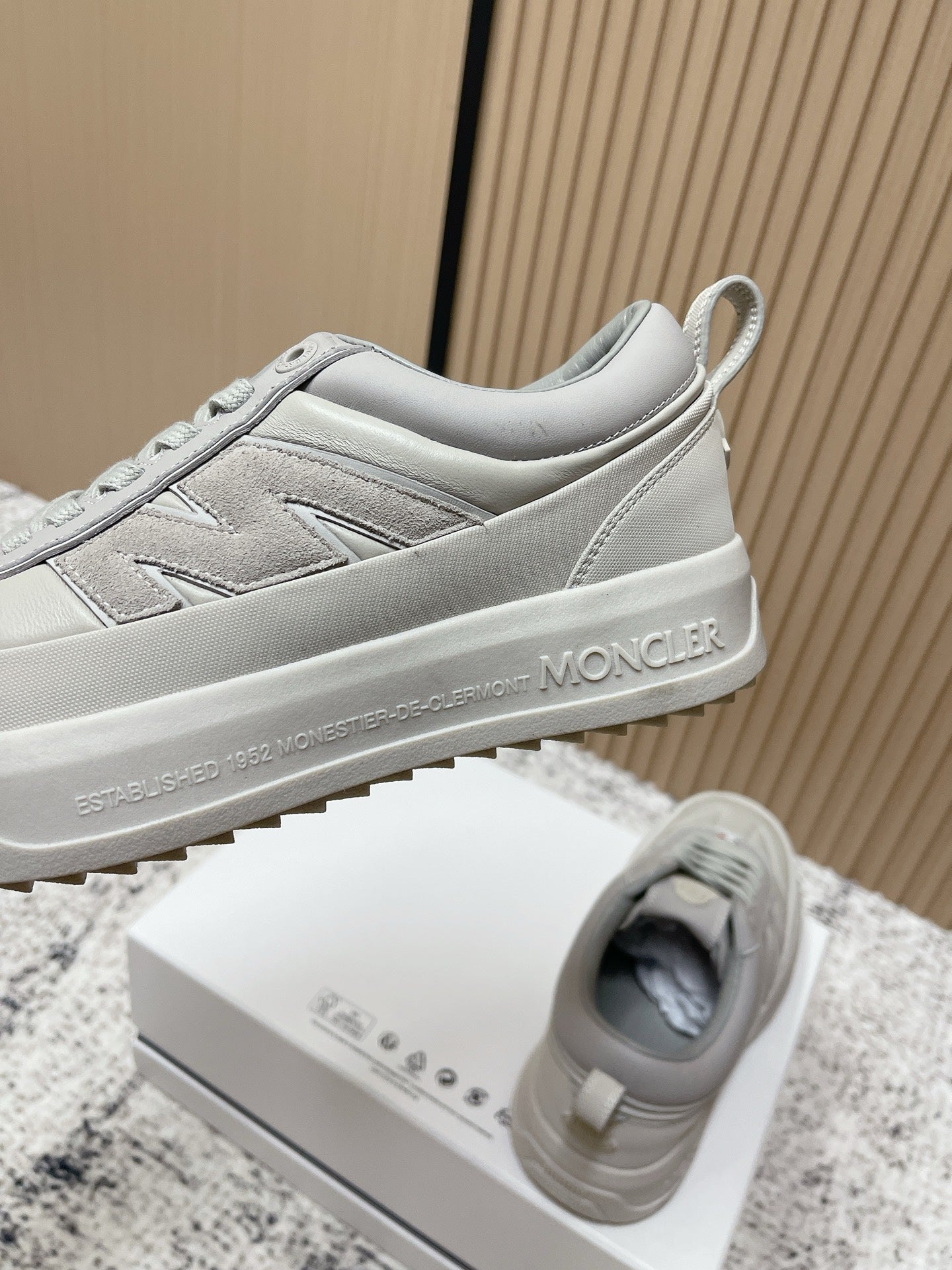 Light gray Moncler low-top sneakers with side panel stitching and heel logo text