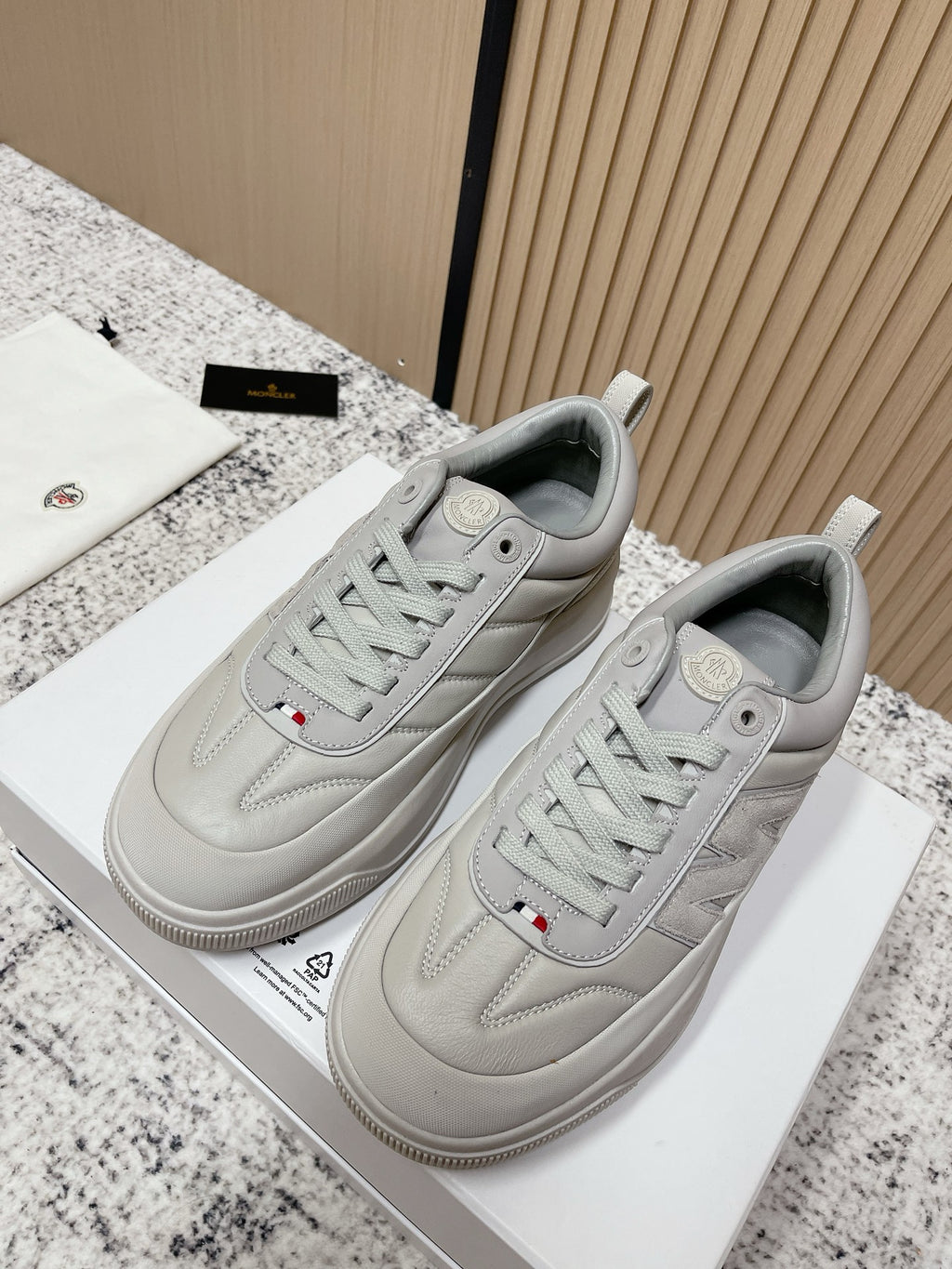 Light gray low-top sneakers with lace-up design and Moncler emblem on tongue