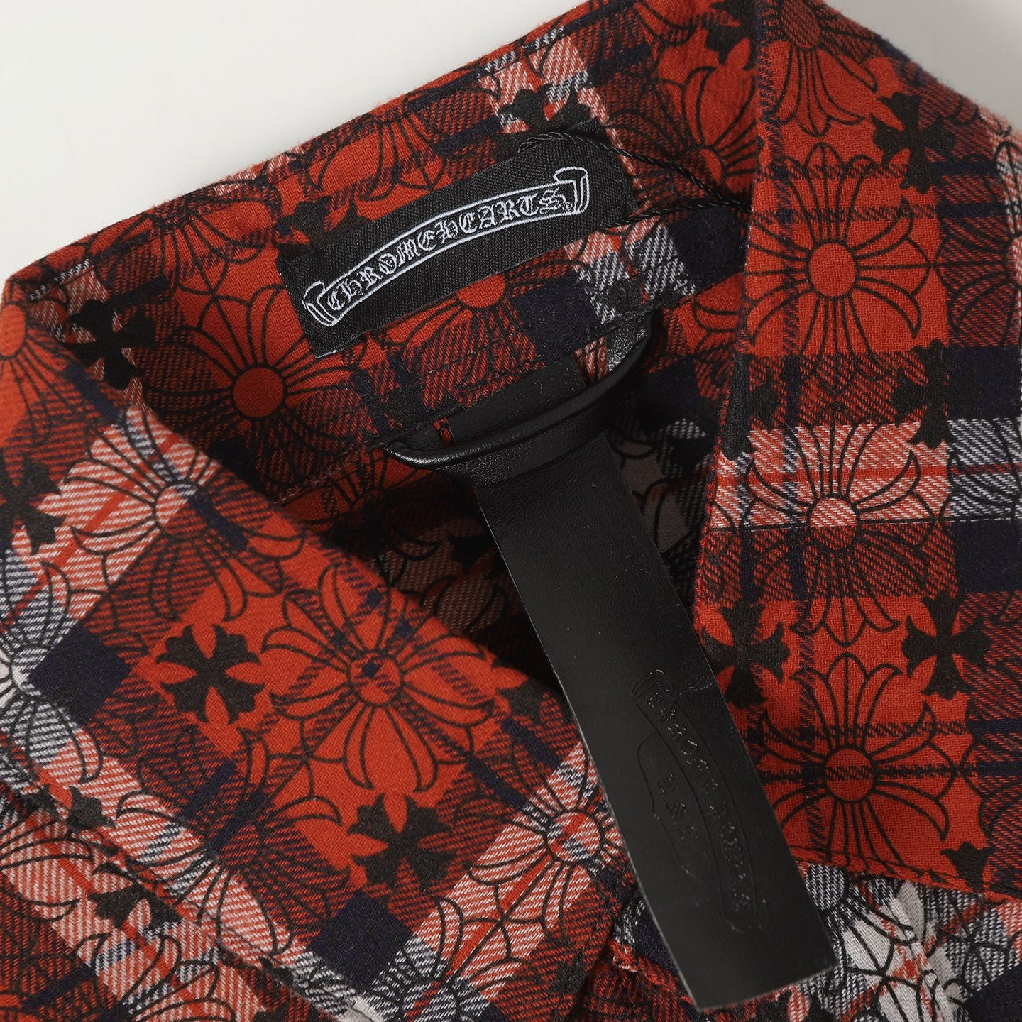 Long-sleeve shirt placket with black snap buttons on red floral plaid fabric