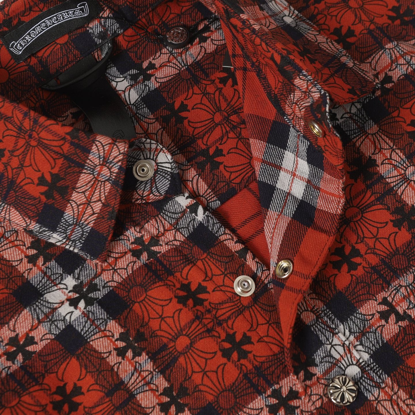 Long-sleeve shirt front with snap buttons and red plaid floral fabric