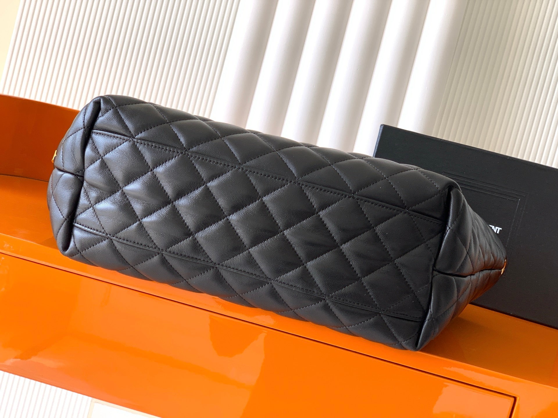 Black quilted leather bag with rolled top handle and diamond stitching