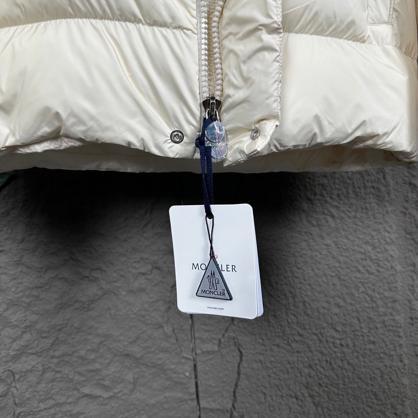 Off-white puffer jacket front with zipper pull and hanging tag