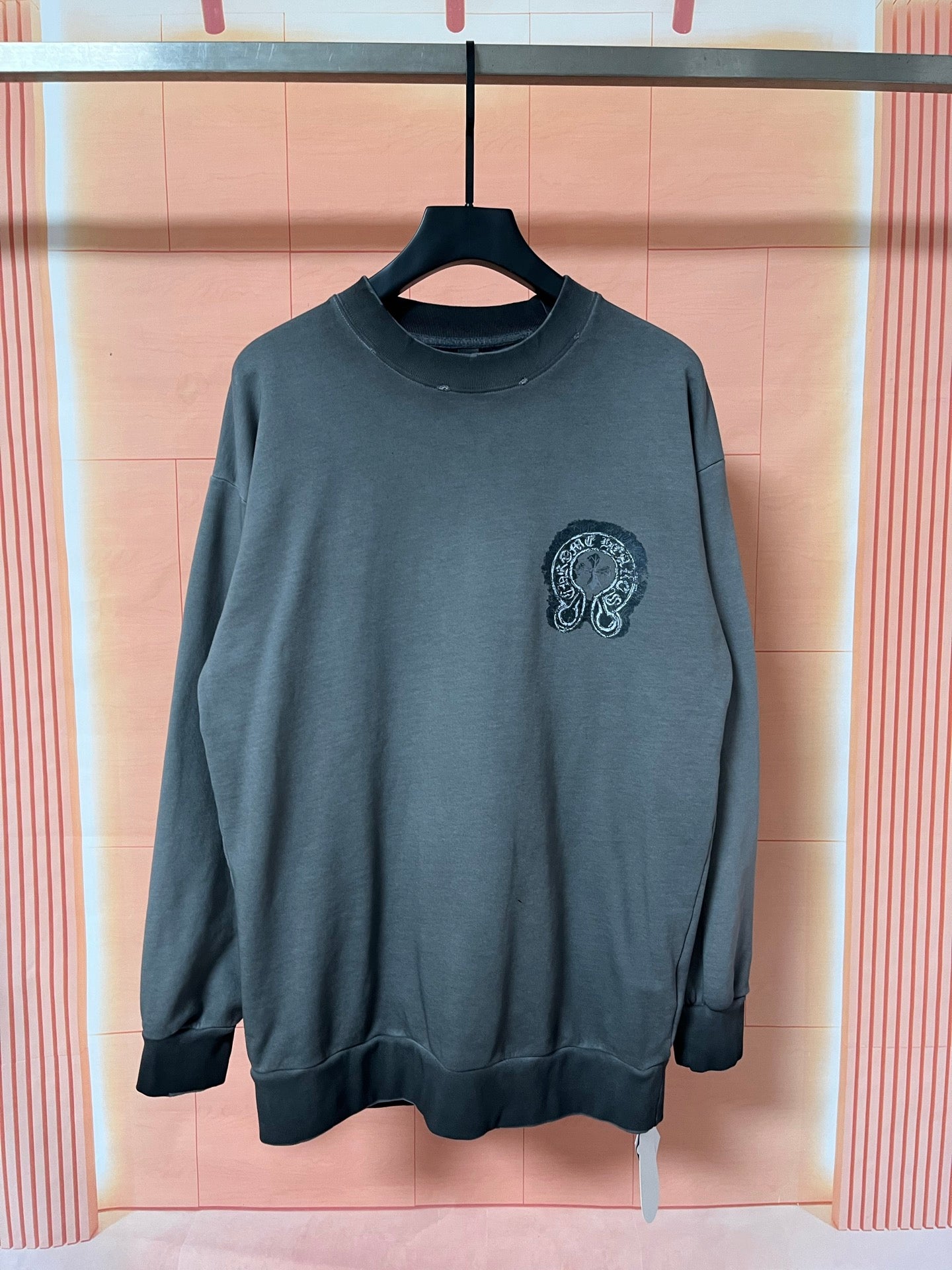 Dark teal long-sleeve sweatshirt with small chest graphic emblem