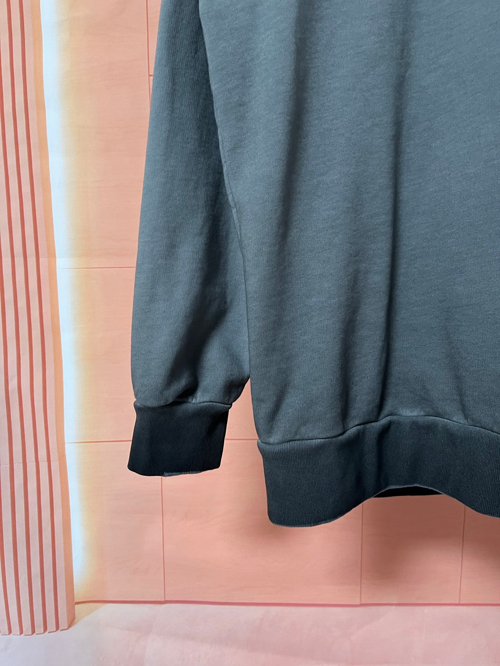 Dark teal sweatshirt sleeve with ribbed cuff and curved hem