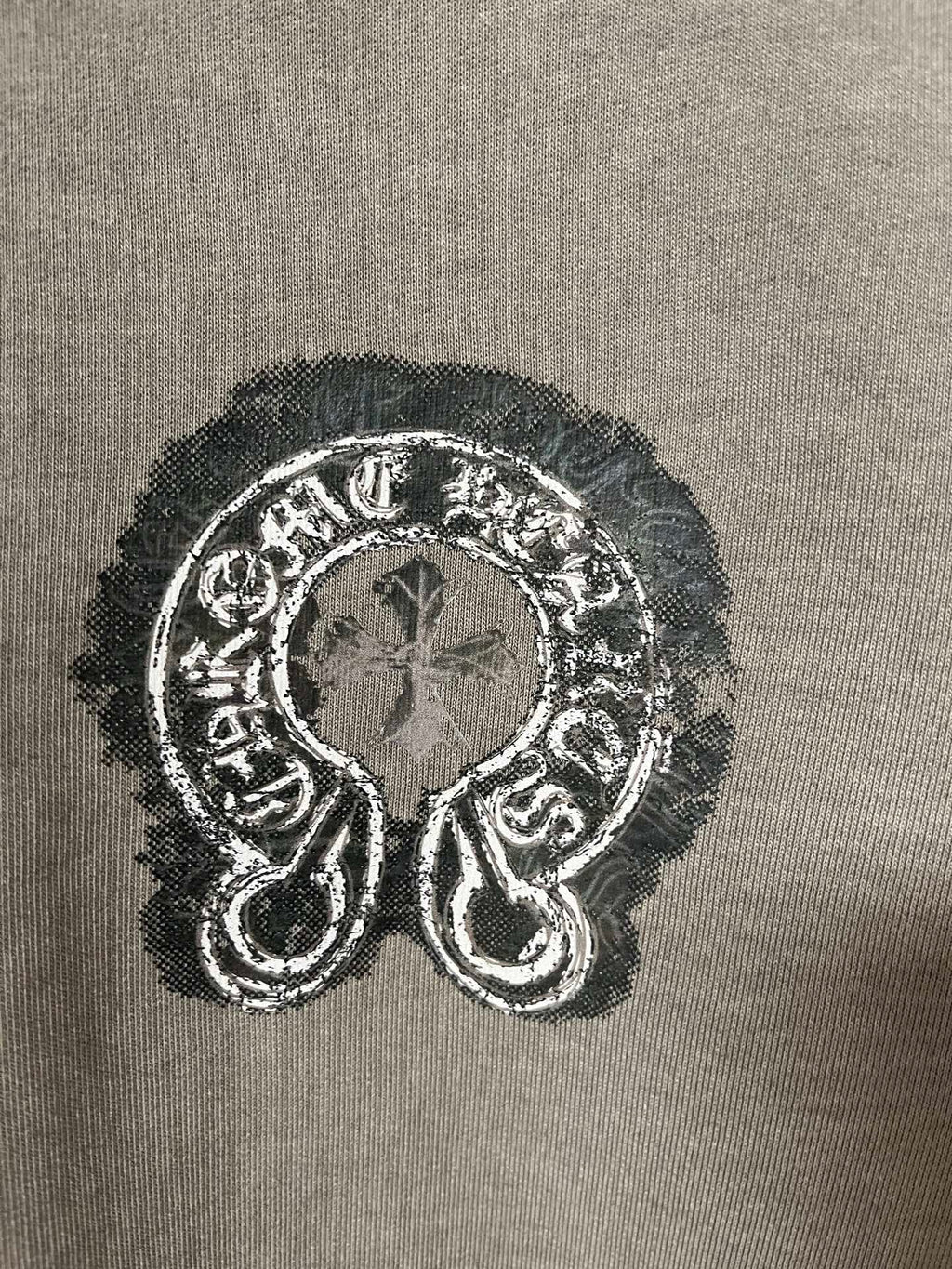 Embroidered graphic emblem on dark teal sweatshirt fabric