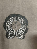 Embroidered graphic emblem on dark teal sweatshirt fabric