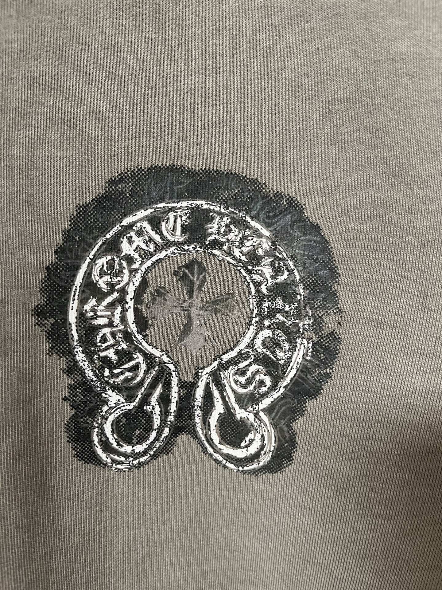 Embroidered graphic emblem on dark teal sweatshirt fabric