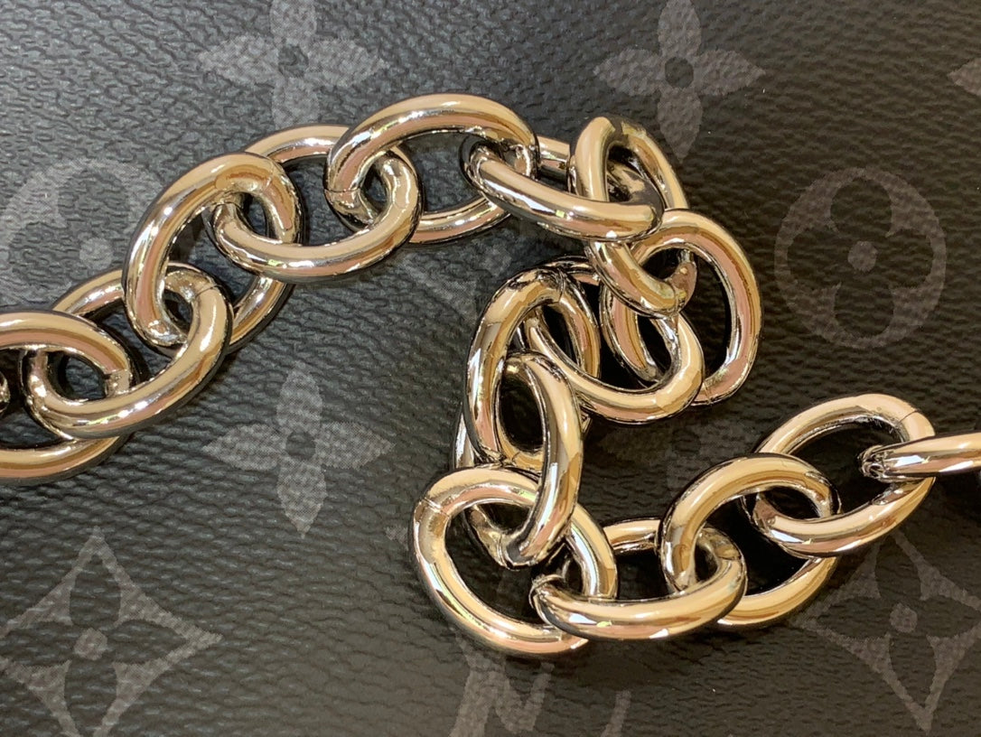 Gold-tone chain links on dark monogram handbag