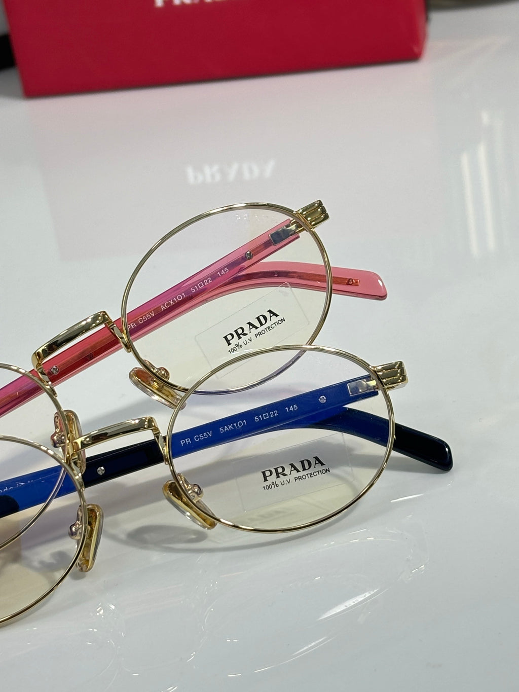 Round eyeglasses close-up with gold frame, red and blue temple sections