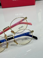 Round eyeglasses close-up with gold frame, red and blue temple sections