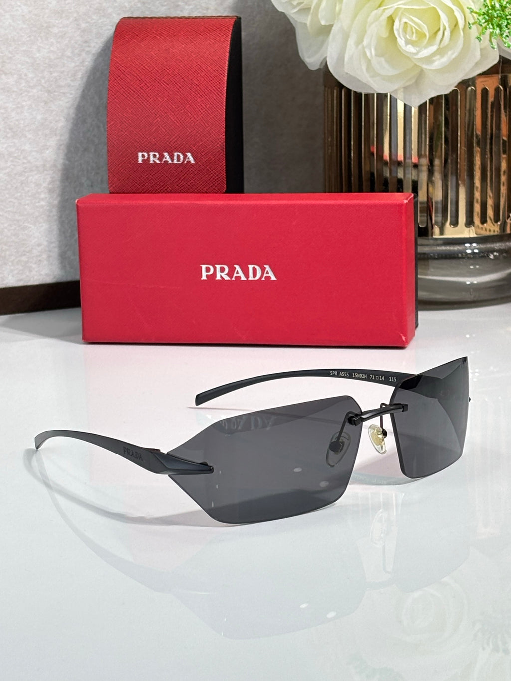 Prada sunglasses with dark lenses and black temples featuring gold accents.