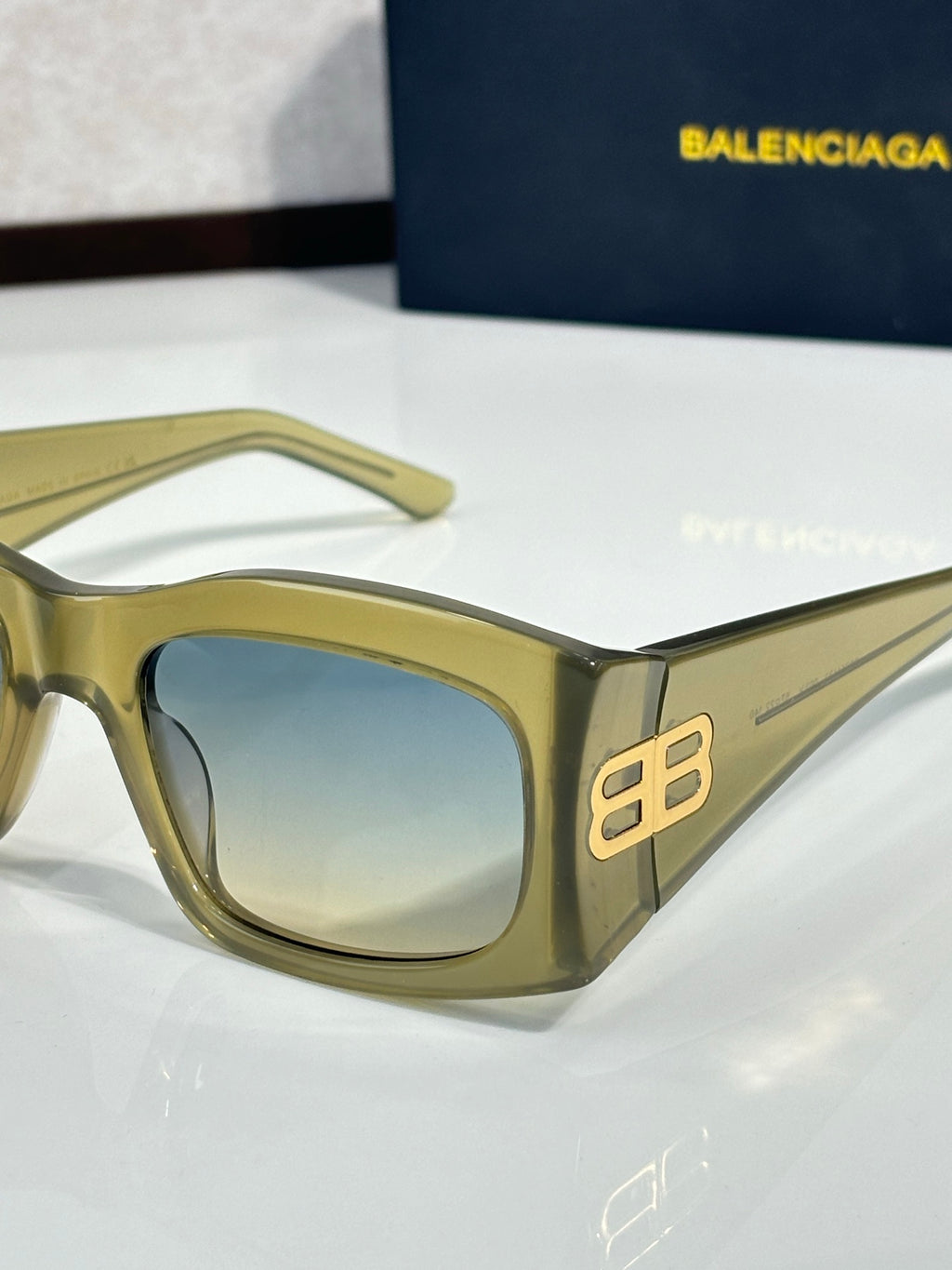 Balenciaga sunglasses with light blue-tinted lenses and gold acetate frame, gold logo