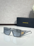 Balenciaga sunglasses with blue-tinted lenses and light gray acetate frame, gold logo