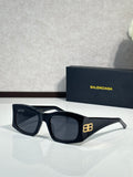 Balenciaga sunglasses with dark lenses and black acetate frame, gold logo detail