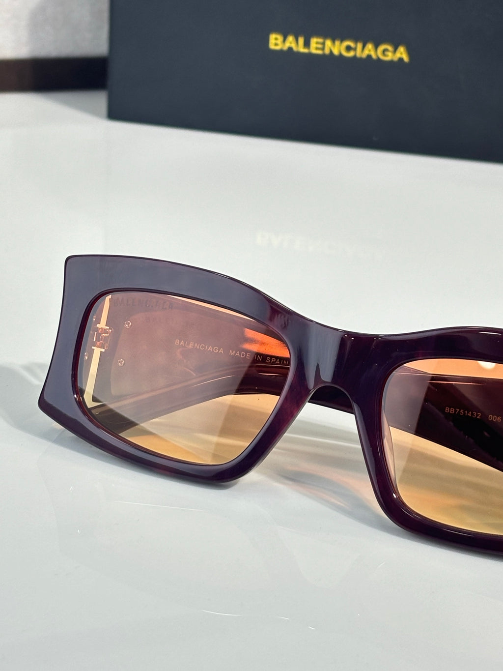 Balenciaga sunglasses with orange-tinted lenses and deep purple acetate frame, gold logo