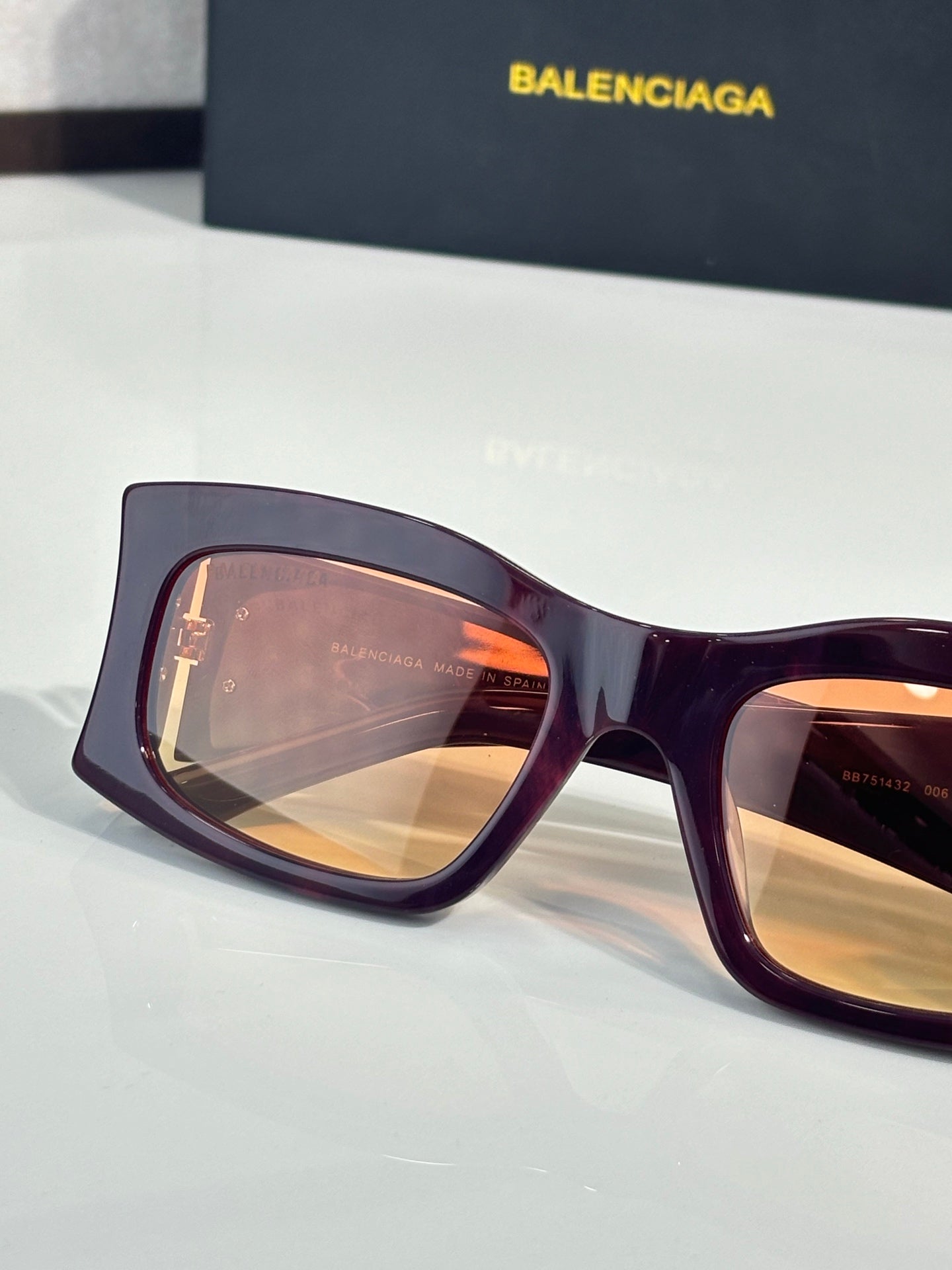 Balenciaga sunglasses with orange-tinted lenses and deep purple acetate frame, gold logo