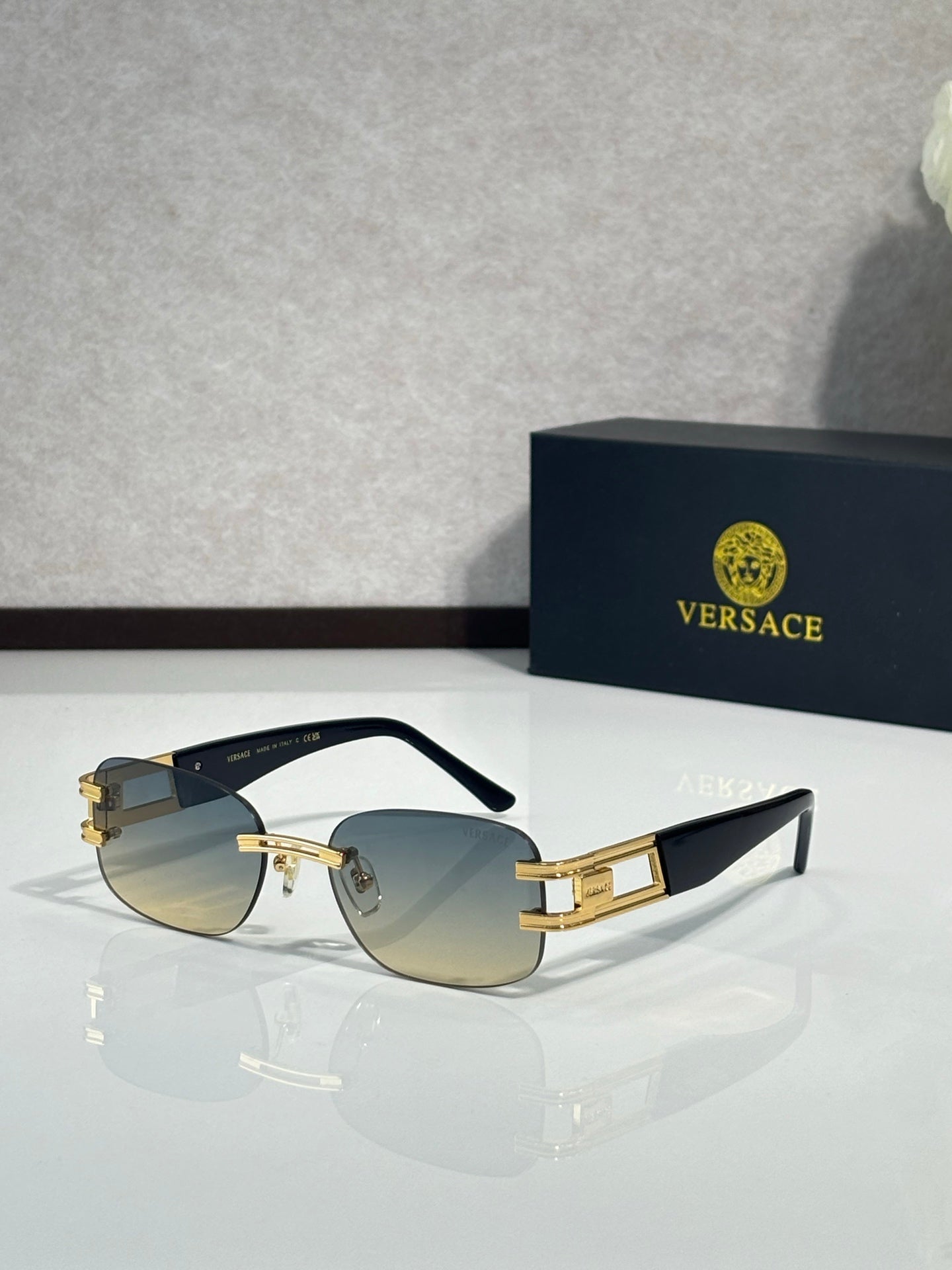 Gold-tone sunglasses with amber gradient lenses and black temple arms with logo text