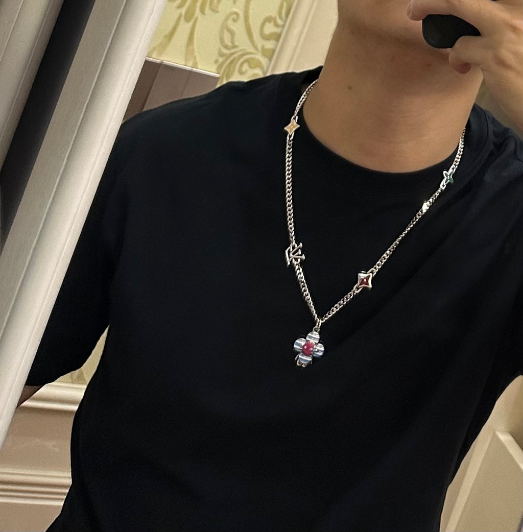 Silver charm necklace worn with black top; multicolor flower and heart pendants