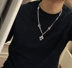 Silver charm necklace worn on black shirt; multicolor flower drop pendant