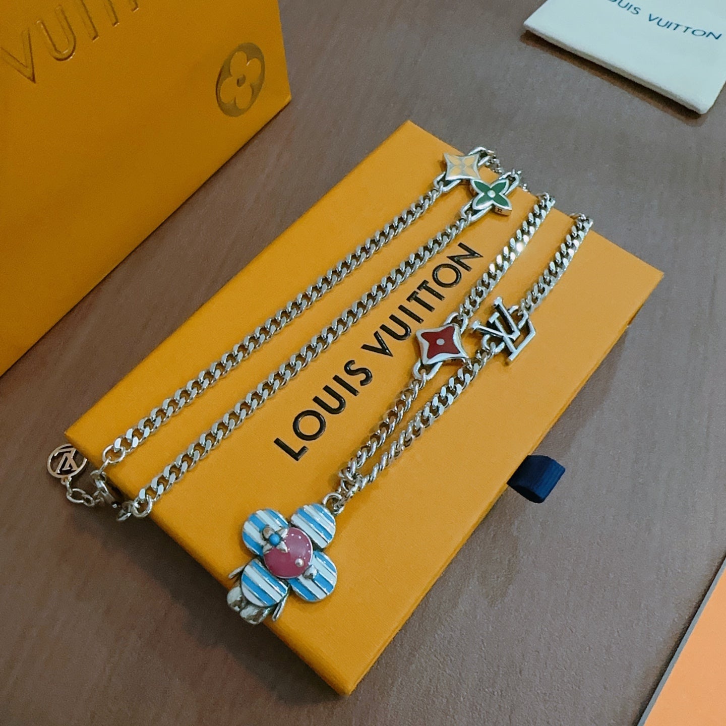 Silver double-chain charm necklace with enamel flower and letter-logo pendant