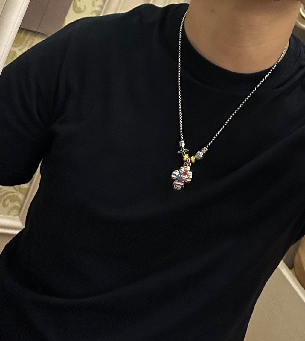 Silver-tone chain charm necklace with small colorful character pendant near the collar