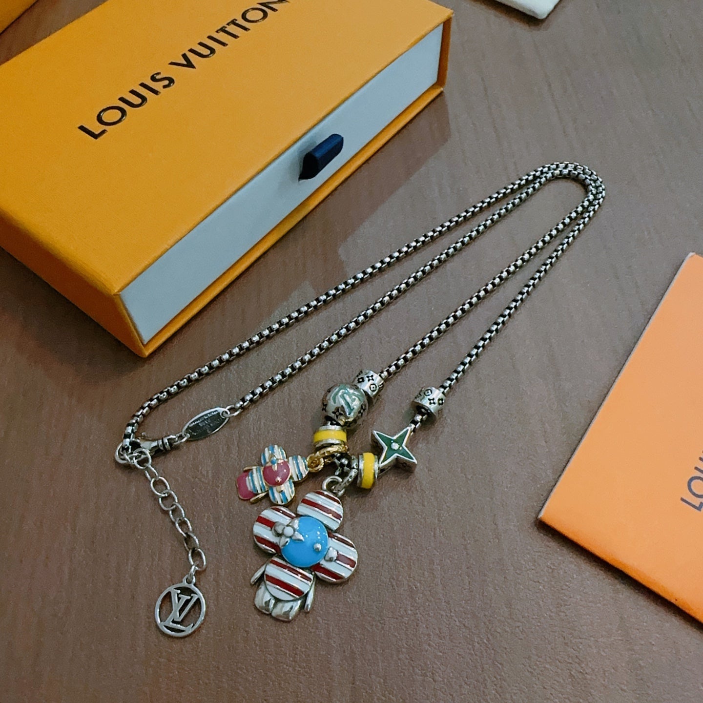 Silver-tone charm necklace with character pendants and star charm, showing lobster clasp