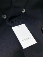 Dark coat with white GUCCI-branded hang tag near button placket