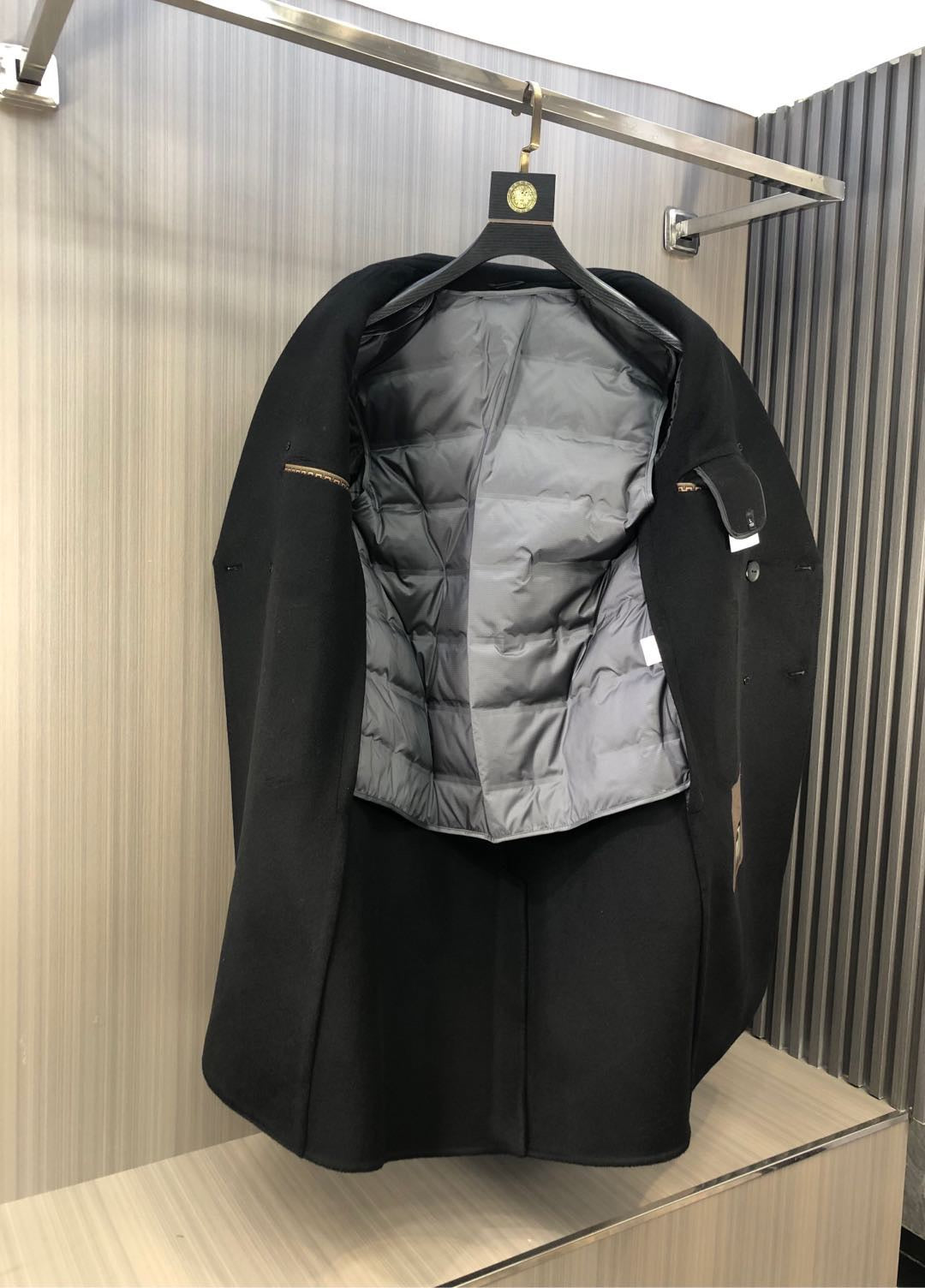 Black long coat with gray quilted inner lining visible when opened