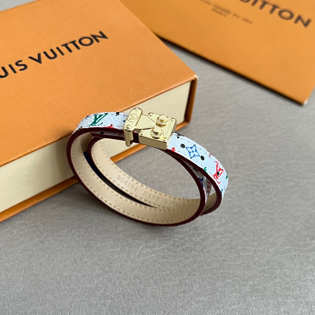 Louis Vuitton bracelet with multicolor print and gold clasp on cream leather strap.
