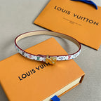 Louis Vuitton bracelet with white multicolor print and gold clasp, cream leather backing.