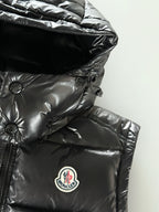 Black Moncler hooded puffer jacket with oval chest logo patch on quilted fabric.