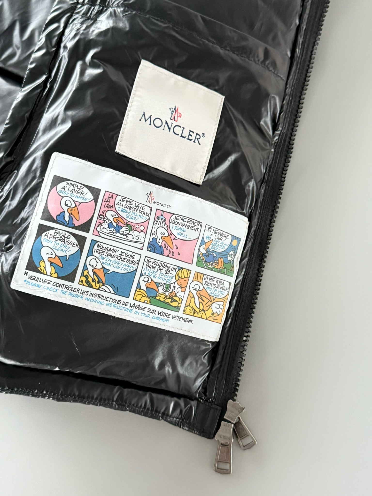 Moncler inner lining with brand label and printed instructions on black puffer jacket.
